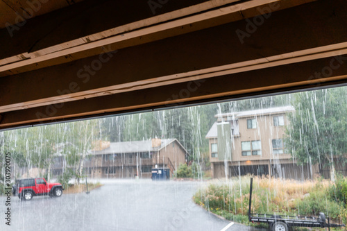 Rainy weather storm in apartment condo complex building with rain water falling outside and foreground of covered roof under balcony