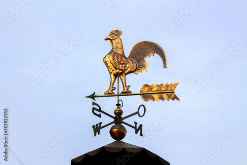 Nice weathercock on a roof with blue sky background photo