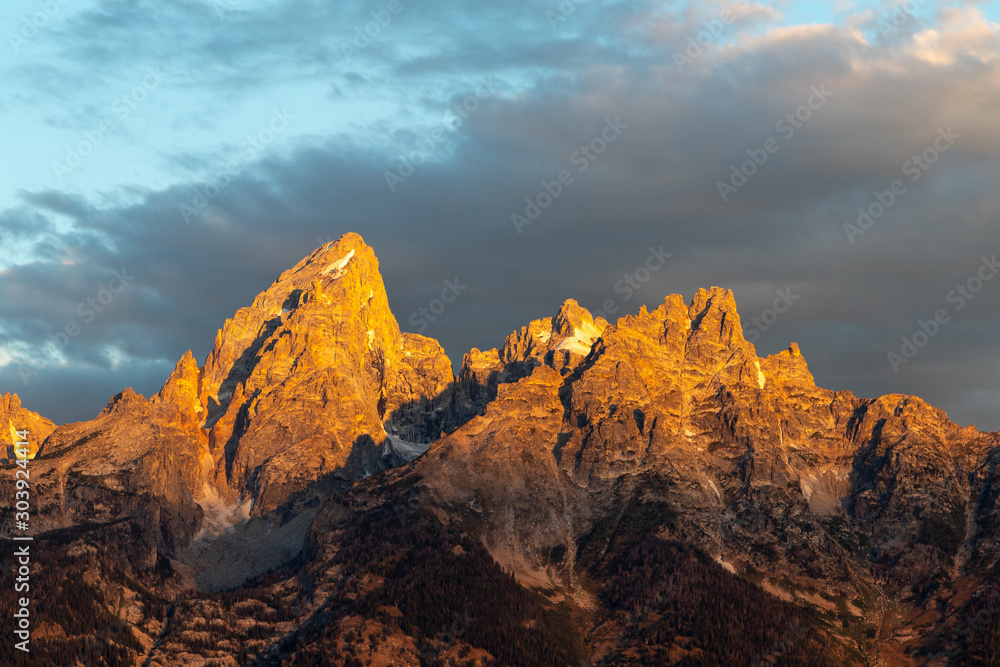The golden peak of a mountain at sunrise  with dark clouds in the beackground