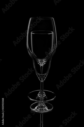 Empty clean wine glasses stand in a row one by one on a dark background with reflection.