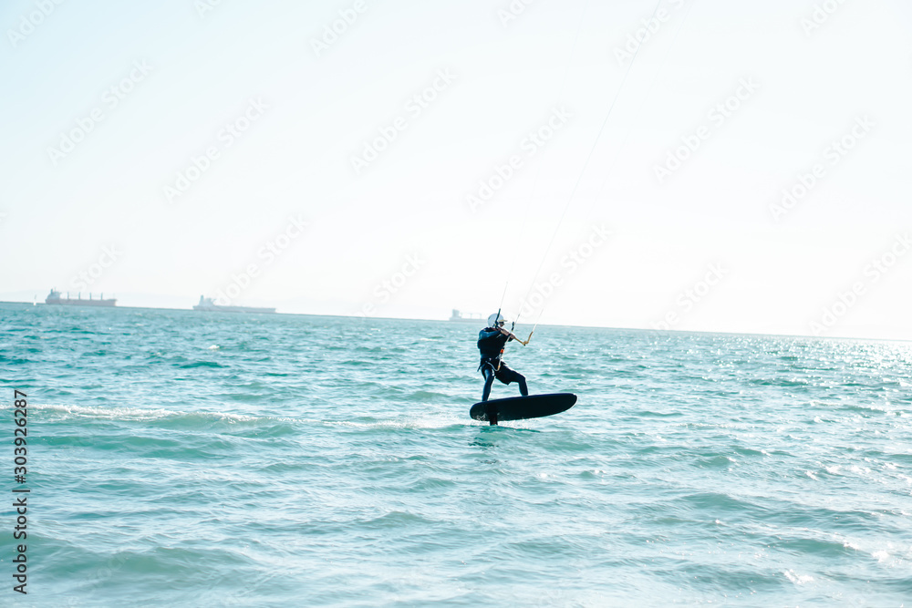 Professional kiter rides on the waves, jumps on the sea.