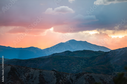 Fototapeta Naklejka Na Ścianę i Meble -  Orange red cloudy sunset sun rays in Aspen, Colorado with rocky mountains peak and vibrant color of clouds at twilight with mountain ridge silhouette
