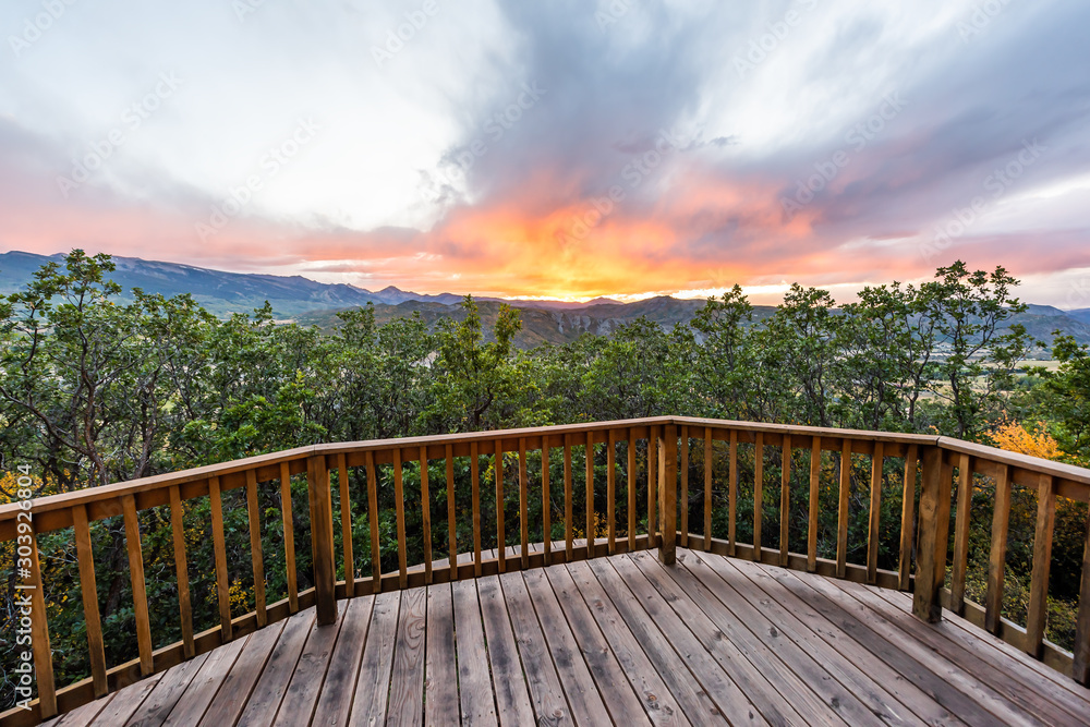 Aspen, Colorado house real estate view with wooden deck railing on balcony terrace and autumn foliage in roaring fork valley in 2019 and sunset