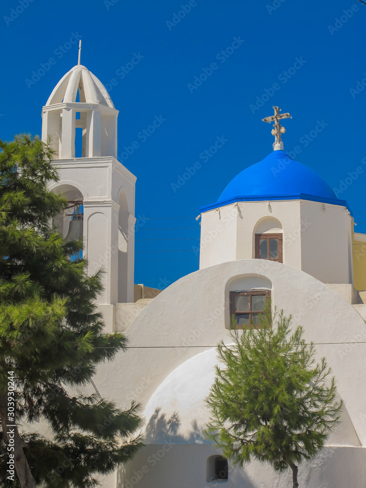 Blue and white Greece church behind the trees
