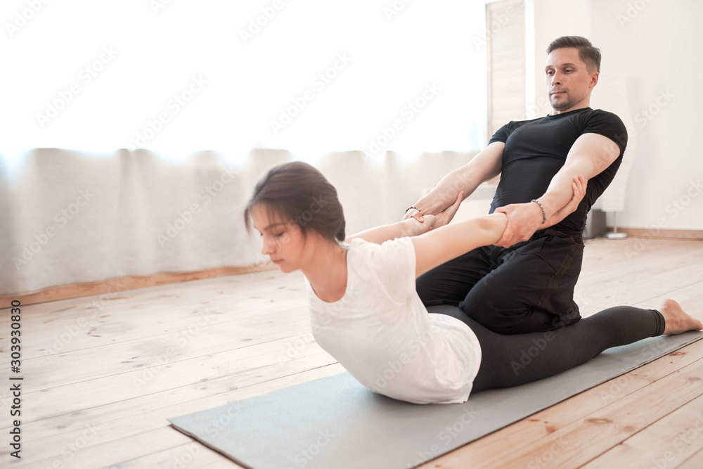 Man and woman in stretching training against background of window in gym Man and woman in stretching training against background of window in gym