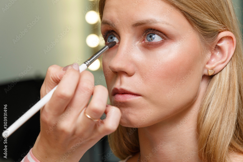The process of creating makeup. Makeup artist working with a brush on the face of the model. The process of creating makeup. Makeup artist working with a brush on the face of the model.