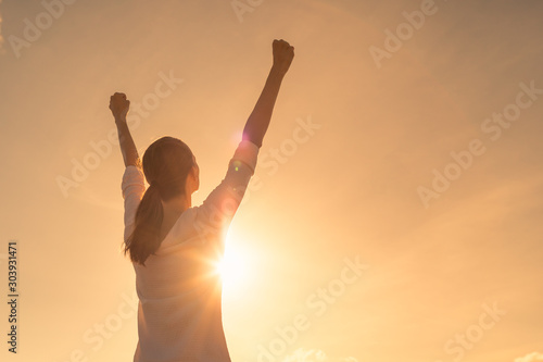 Strong young woman with arms up to the sky. People winning and victory concept.