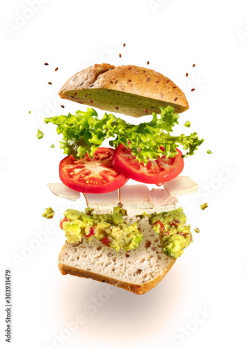 Exploded vegetarian sandwich with guacamole and tofu on white