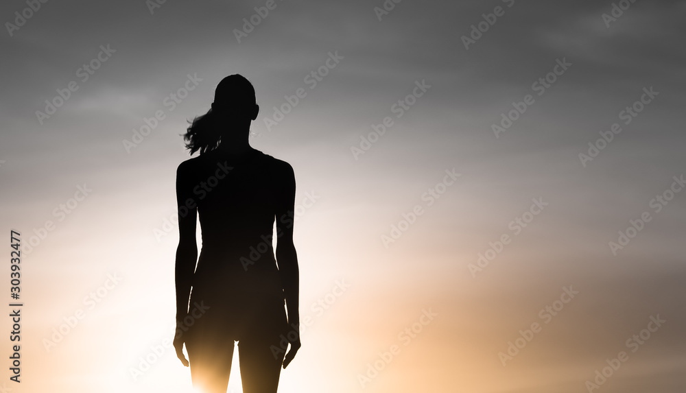 Silhouette of woman standing facing the sunset
