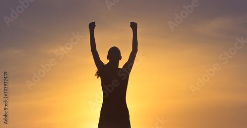 Young female celebrating victory on top a mountain. 