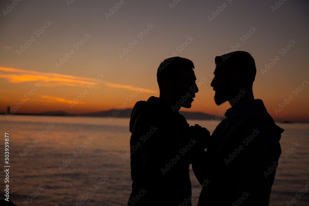 The couple jumping on the seaside on the sunset background