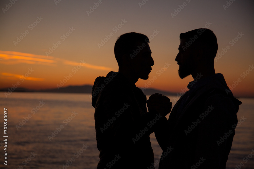 The couple jumping on the seaside on the sunset background