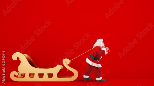 Santa Claus drags a big golden sleigh on a red background photo