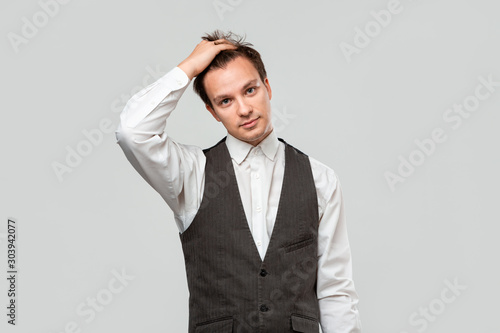 Tired young business man holding hand on head covering face isolated over grey nackground.