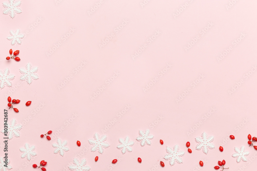 Elegant winter background with copy space. Red berries and snow flakes on pale pink background. Christmas, winter holiday, new year concept.	
