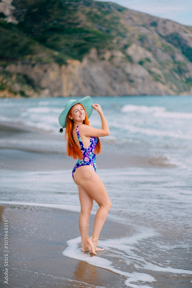 Happy woman in swimsuit stands on beach