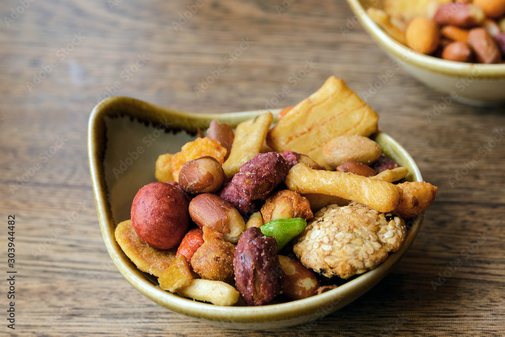 Nuts and cookies seasoned with salt and spices in a small plate on a wooden table. Great beer snack. Spicy snacks. Nuts and cookies seasoned with salt and spices in a small plate on a wooden table. Great beer snack. Spicy snacks.