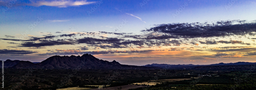Sunset, aerial landscapes of Santa Rita Mountains from above Tubac, Arizona with warm , golden plains, purple mountains, blue sky with colorful clouds on a Fall day Sunset, aerial landscapes of Santa Rita Mountains from above Tubac, Arizona with warm , golden plains, purple mountains, blue sky with colorful clouds on a Fall day