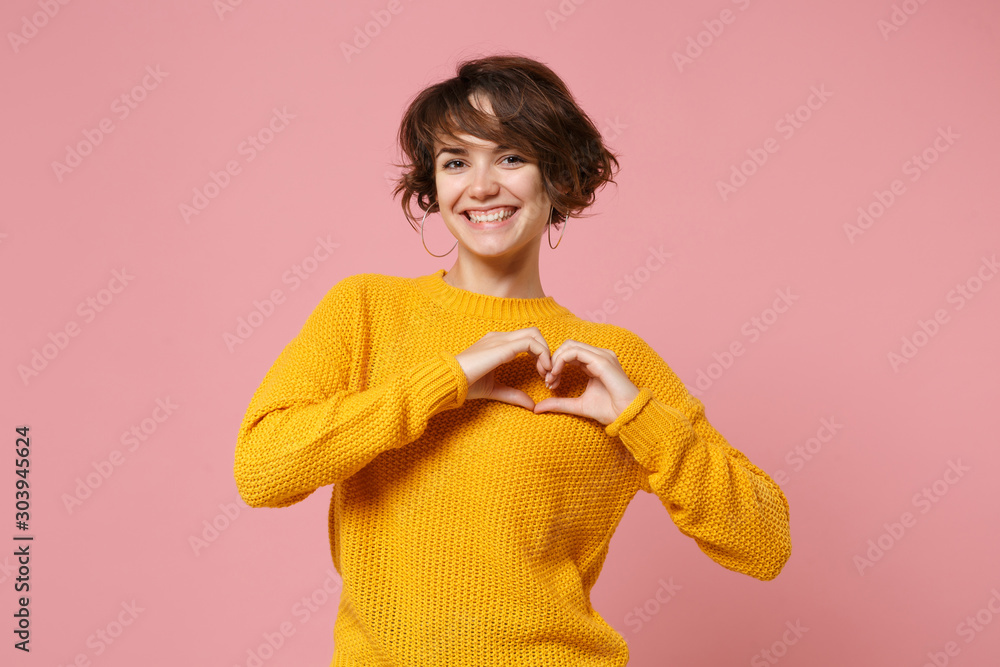 Φωτογραφία Smiling young brunette woman girl in yellow sweater posing isolated on pastel pink background in studio