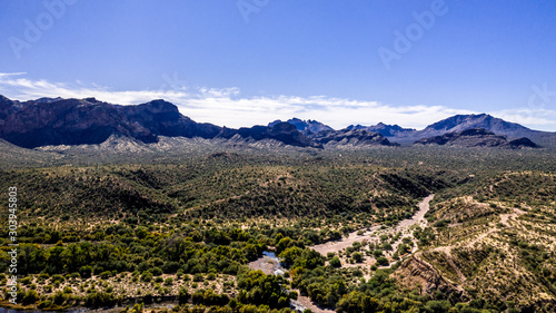 Aerial  landscape along the Salt River in Arizona with pink and orange rocks  purple mountains  cool water  blue sky  cactus  green trees and brush on a Fall day