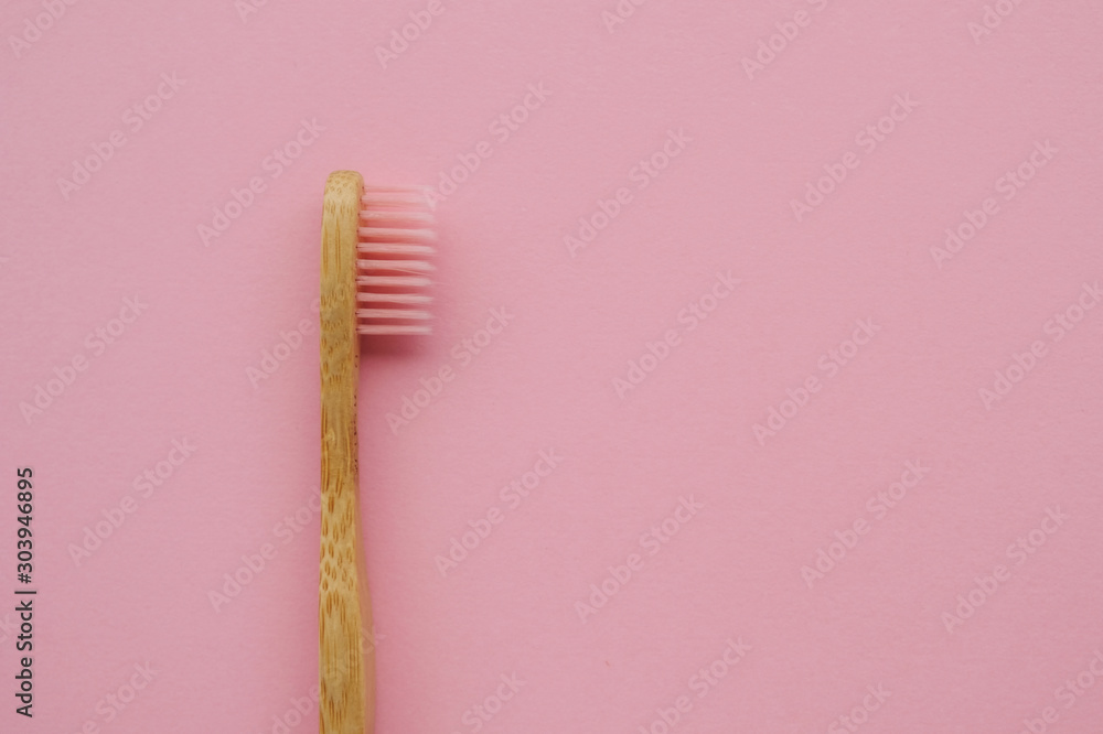 Stylish eco friendly natural toothbrush with wooden bamboo handle on pink background. Oral hygiene concept. Space for text. Flat lay style, top view. Reduce plastic waste, sustainable lifestyle. Stylish eco friendly natural toothbrush with wooden bamboo handle on pink background. Oral hygiene concept. Space for text. Flat lay style, top view. Reduce plastic waste, sustainable lifestyle.