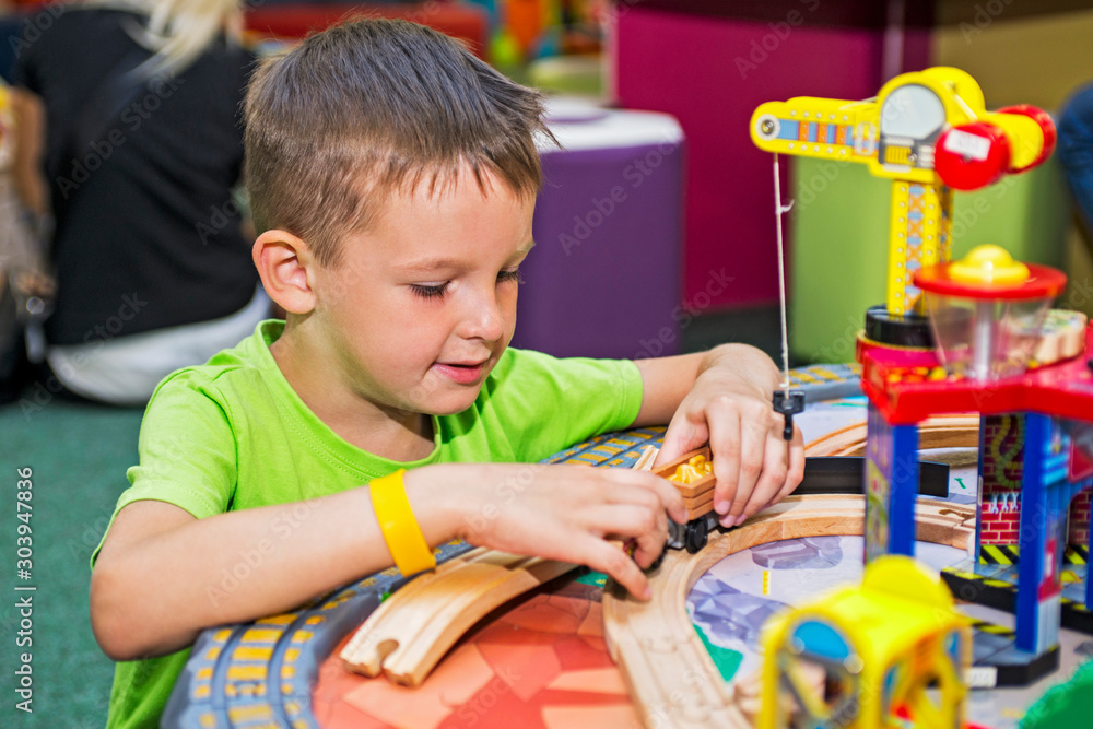 Φωτογραφία Child boy plays with wooden toy, builds toy railroad at home or daycare