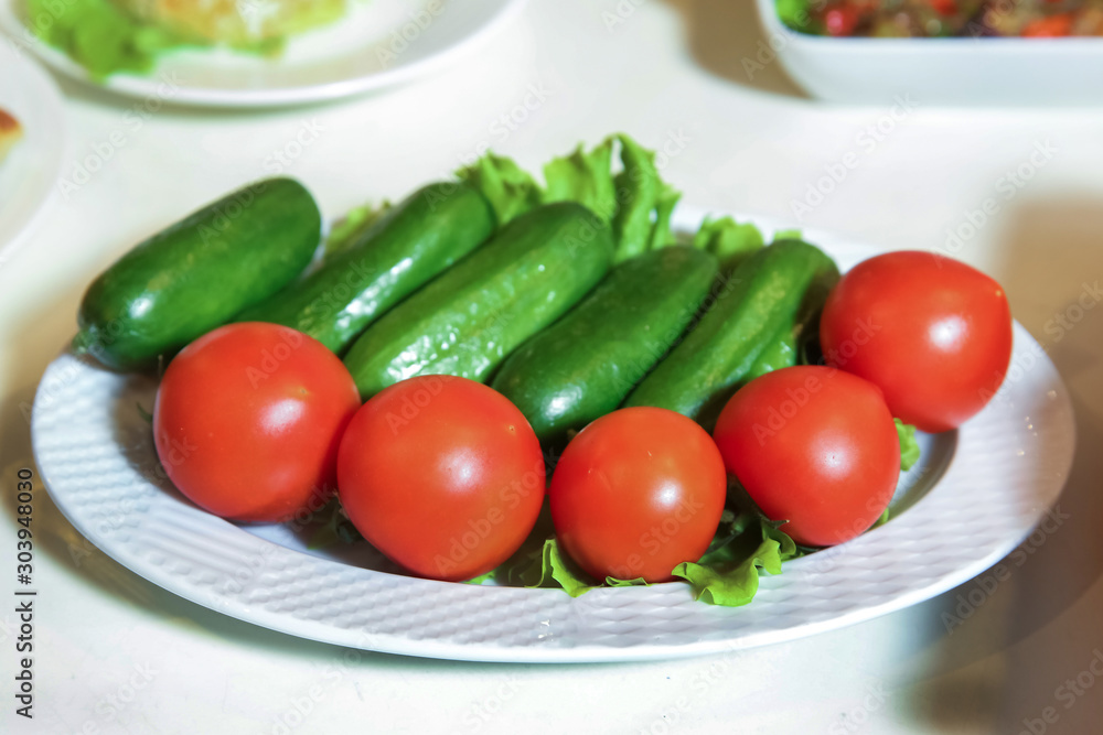 Vegetarian salad with cucumbers, tomatoes . Vegan salad on a white plate. breakfast top view . Cucumbers and tomatoes on a white plate. Vegetarian salad with cucumbers, tomatoes . Vegan salad on a white plate. breakfast top view . Cucumbers and tomatoes on a white plate.