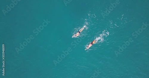 Two swimmers practicing in a long distance swim at calm ocean water. Top Down aerial Image..