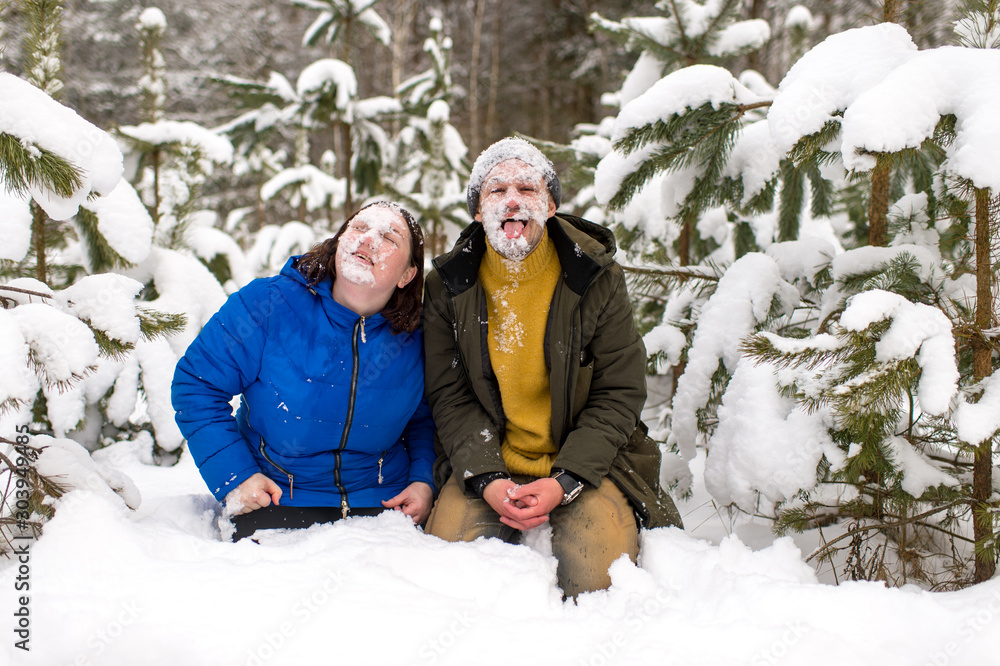 Obraz premium Portrait of funny couple with thier faces covered with snow standing on knnes in snowy forest