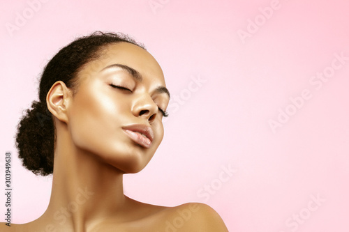 African American skincare models portrait. Beauty spa treatment concept.Young girl posing with closed eyes against pink background photo