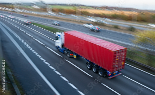 Lorry with red shipping container in motion on British motorway M1