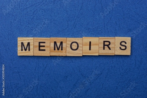 word memoirs made from brown wooden letters lies on a blue table  