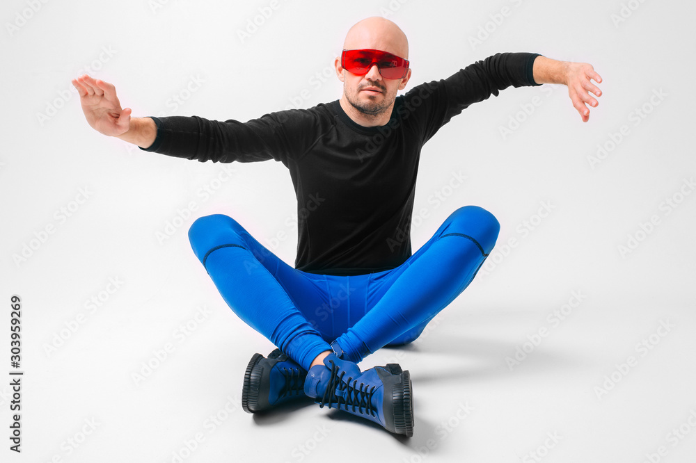 Strange man in stylish clothes and red sunglasses relaxing in studio against white background.