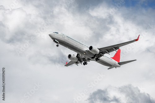 Plane with two turbofan engines  landing gear and red winglets on cloud background