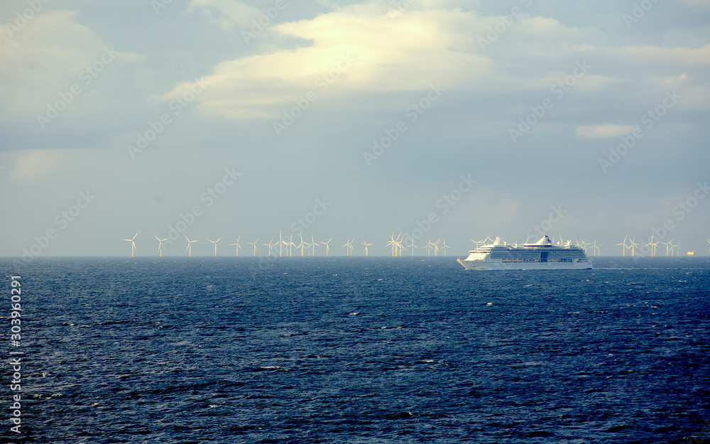 Cruise ship in open sea with wind generators at background