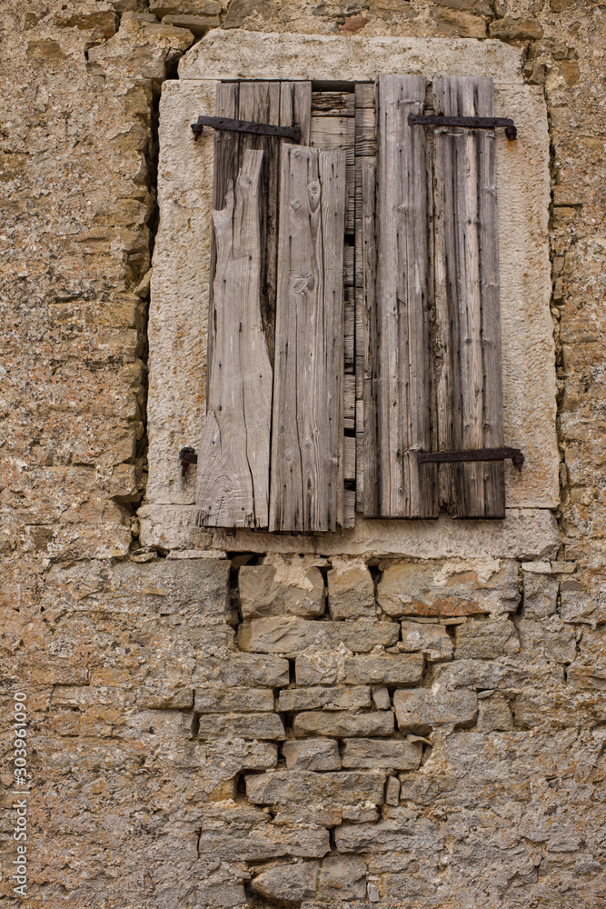 Ancient windows with closed shutters in aged stone wall Ancient windows with closed shutters in aged stone wall