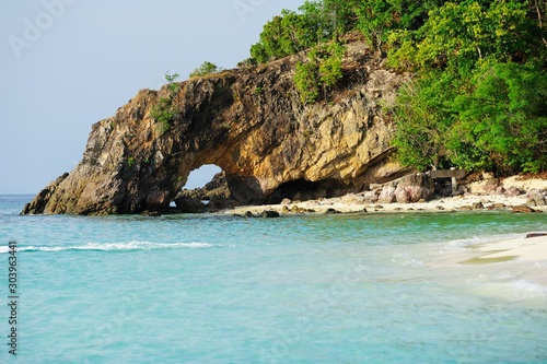 Talu Island. Koh Talu in Tarutao National Park of Satun province Thailand. Mountain and beach with blue sky cloudy. Cave entrance. Cave hole inside. Mountain hole. Sea and mountain hole