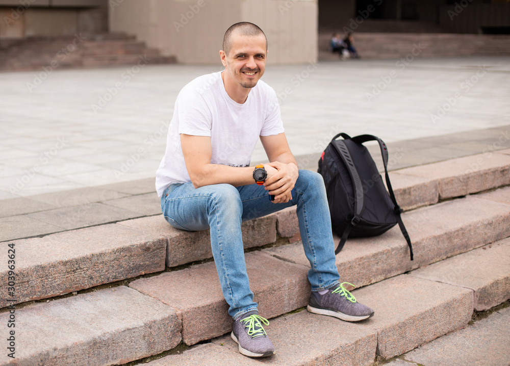 Man looking in camera and smiling while sitting on stairs Man looking in camera and smiling while sitting on stairs