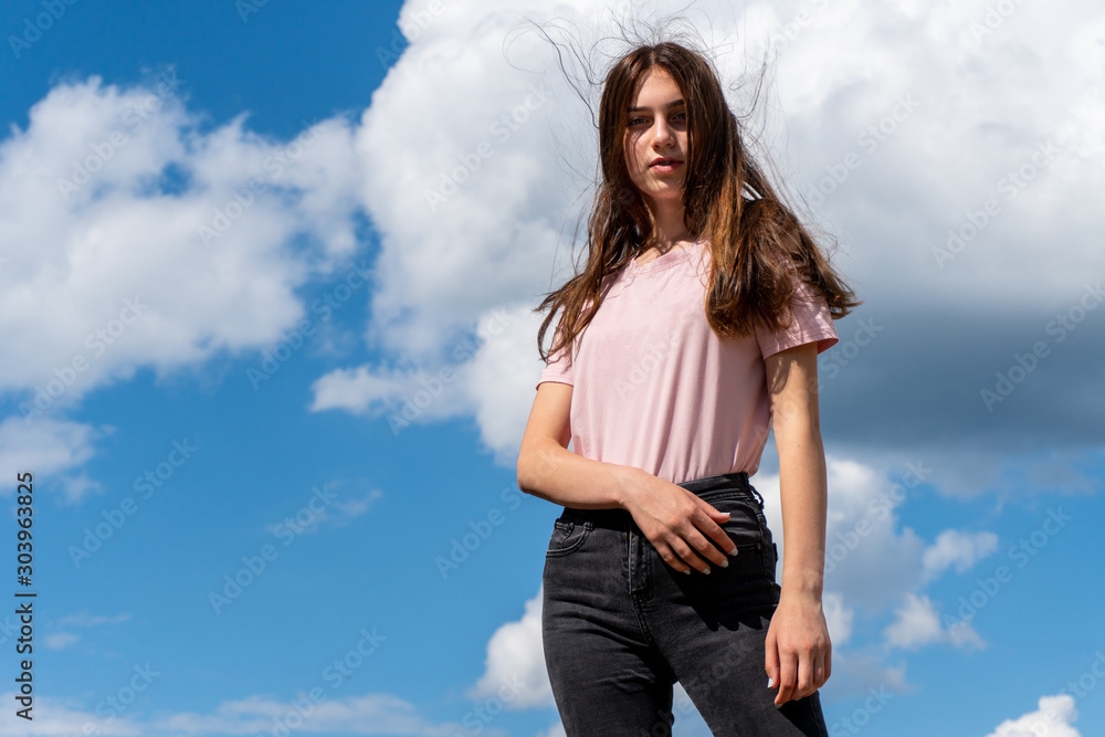 Teen girl looking in camera and posing with sky at background Teen girl looking in camera and posing with sky at background