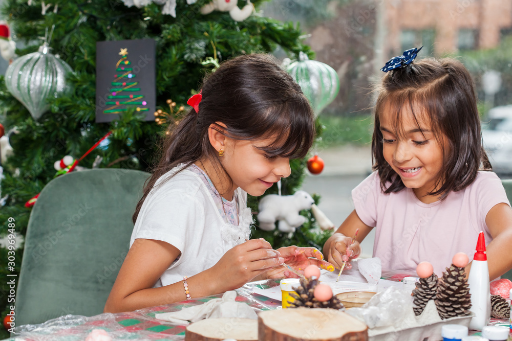 Two little sisters having fun while making christmas Nativity crafts with at home - Real family Two little sisters having fun while making christmas Nativity crafts with at home - Real family