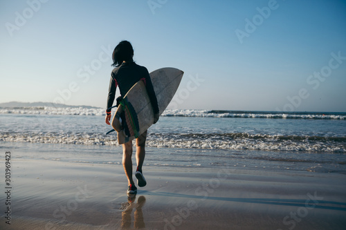 Woman surfer with surfboard on beach