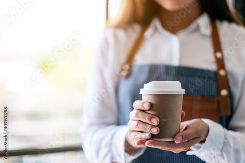 A waitress holding and serving a paper cup of hot coffee in cafe