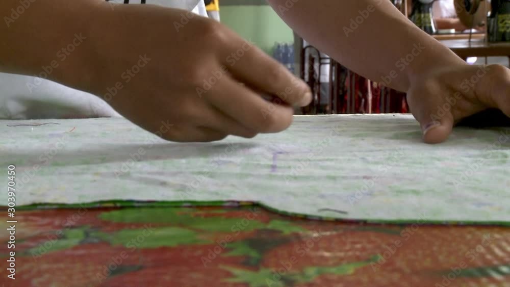 A daylight extreme closeup shot of a local factory worker scoring a white felt fabric on top of the table using a tailor s chalk and long ruler. A daylight extreme closeup shot of a local factory worker scoring a white felt fabric on top of the table using a tailor s chalk and long ruler.