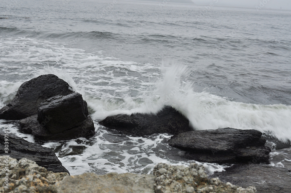 strong smeared waves beating on black stones in a stormy sea strong smeared waves beating on black stones in a stormy sea