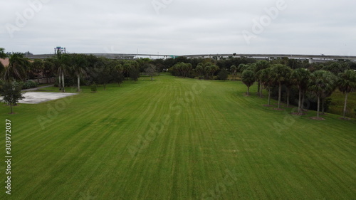 a drone shot overloking a feild with some trees and a highway in the background