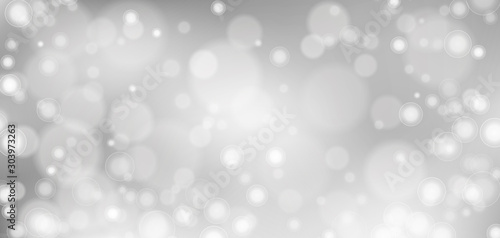 Silver bokeh background. Christmas glowing lights with sparkles. Holiday decorative effect.