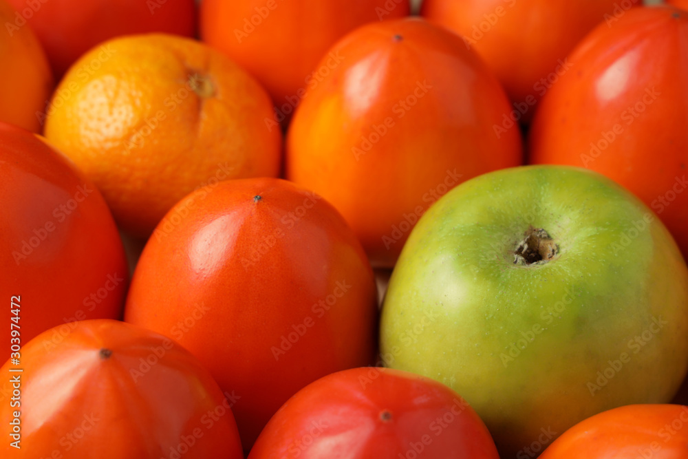Juicy persimmon green apple and sweet tangerine closeup.