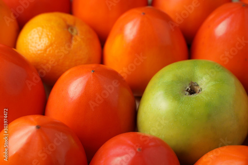 Juicy persimmon green apple and sweet tangerine closeup.