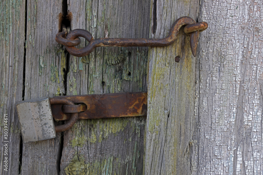 Old and rusty hook locks the old dried up wooden barn door. Old wooden door with locker, close-up, full frame.....