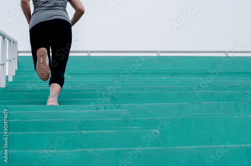 Woman runner feet exercising to running on stairway in gym , She is jogging, fitness workout wellness concept, selective focus